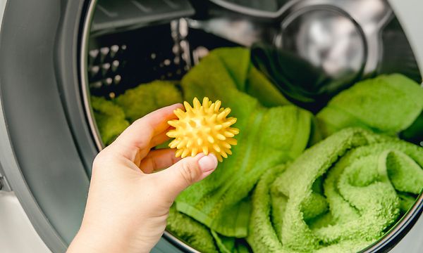 Kuivausrumpu - Käsin laittamassa keltaista kuivauspalloa kuivausrumpuun