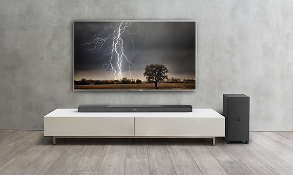 Seinälle kiinnitetty televisio modernissa olohuoneessa ja soundbar sekä subwoofer sen vieressä