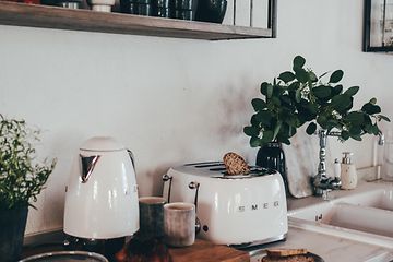 Valkoinen Smeg-leivänpaahdin keittiön työtasolla yhdessä valkoisen teekeittimen kanssa