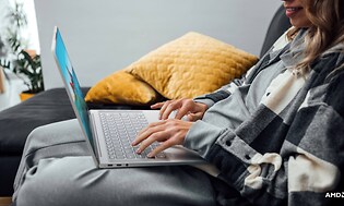 Lenovo Yoga Slim 7 Carbon - Sohvalla istuva nainen kannettava tietokone sylissään