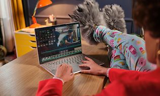 Lenovo Yoga Slim 9 - Nainen editoi videota rennosti jalkojensa ollessa pöydän päällä suoristettuina