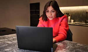 Lenovo Yoga Slim 7 Pro X - Nainen istuu keittiössä kannettava tietokone edessään