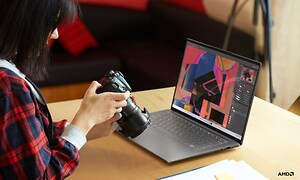 Lenovo Yoga Slim 7 Pro X - Nainen pitelee DSLR-kameraa kannettavan tietokoneen edessä