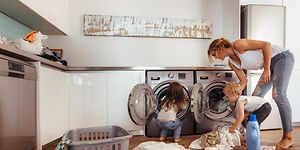 Nainen ja kaksi lasta täyttävät pyykinpesukonetta