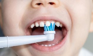  Lapsi harjaa hampaitaan sähköhammasharjalla