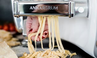 Henkilö käyttää Ankarsrum-yleiskonetta pastan valmistamiseen