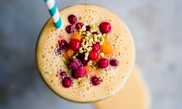 Oranssi, marjoilla koristeltu smoothie ja pilli lasissa 