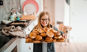 Tyttö, joka pitelee korvapuustitarjotinta
