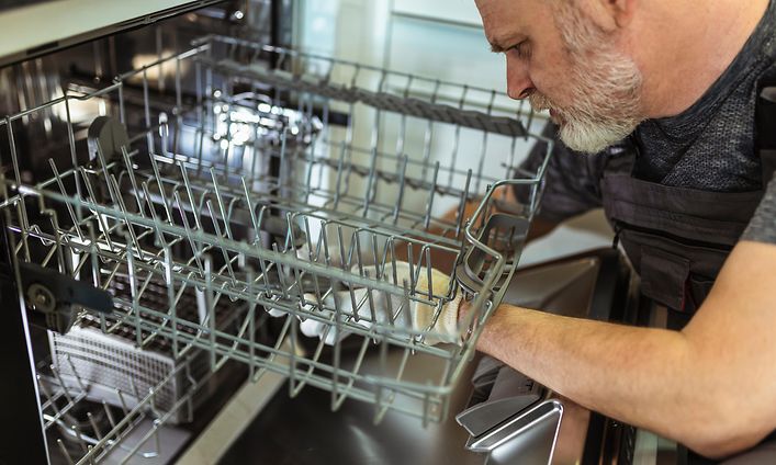 Mies korjaamassa astianpesukonetta