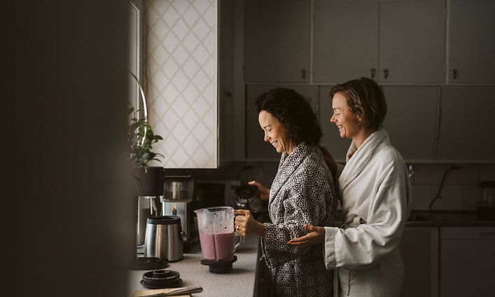 Naiset keittiössä tehosekoittimen äärellä