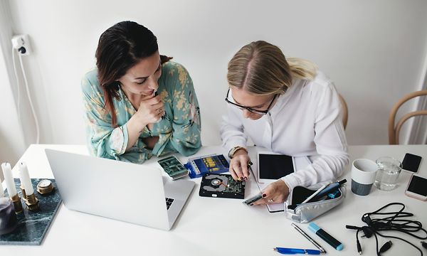 Kaksi naista korjaamassa elektroniikkalaitetta yhdessä