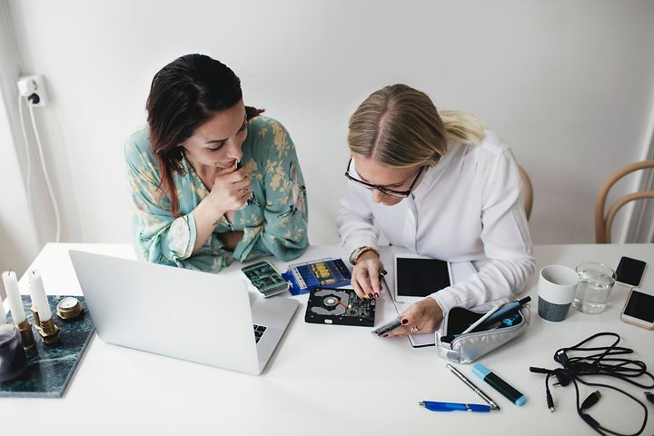 Kaksi naista korjaamassa elektroniikkalaitetta yhdessä