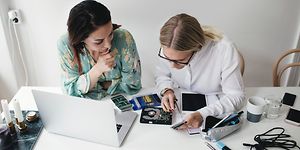 Kaksi naista korjaamassa elektroniikkalaitetta yhdessä