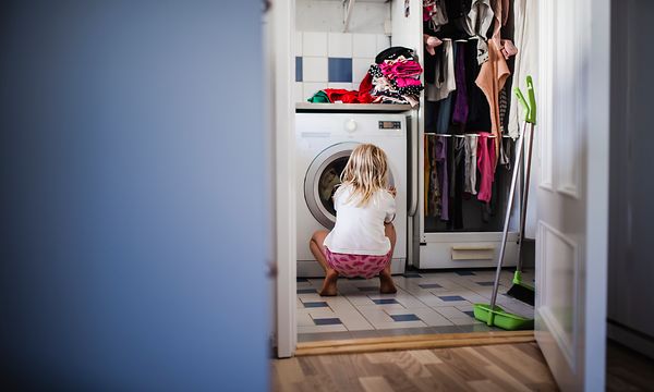 Tyttö katsoo pyykinpesukoneen sisälle
