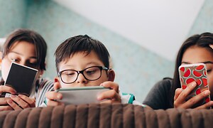 Mitä sinun tulisi tehdä, jos älypuhelimesi näyttö menee rikki - Kolme lasta sängyllä älypuhelimiensa kanssa