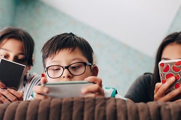 Mitä sinun tulisi tehdä, jos älypuhelimesi näyttö menee rikki - Kolme lasta sängyllä älypuhelimiensa kanssa