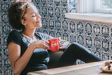 Nainen nautiskelee kahvia punaisesta kupista, jossa Melitta-logo