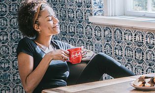 Nainen nautiskelee kahvia punaisesta kupista, jossa Melitta-logo