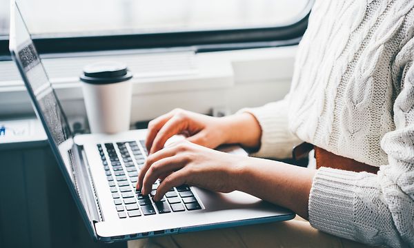 Junassa oleva nainen työskentelee kannettavalla tietokoneellaan