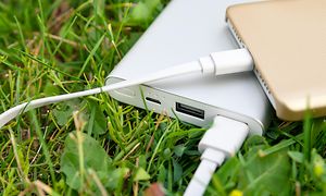 Ruohikossa oleva powerbank-varavirtalähde lataamassa älypuhelinta