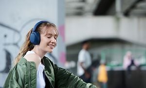 Hymyilevä nuori nainen siniset Sony WH-XB910 -kuulokkeet päässään