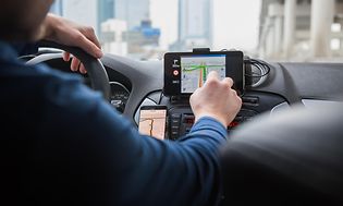 Mies käyttää GPS-navigaattoria autossa