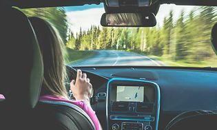 Nainen ajaa autoa, jossa on GPS-navigaattori