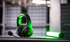 Razer-pelikuulokkeet pöydällä vihreän valon vieressä