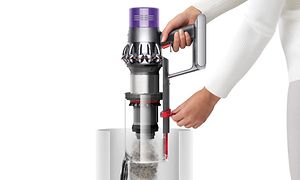 Nainen tyhjentämässä Dyson V10 -varsi-imurin pölysäiliötä "point and shoot" -mekanismin avulla