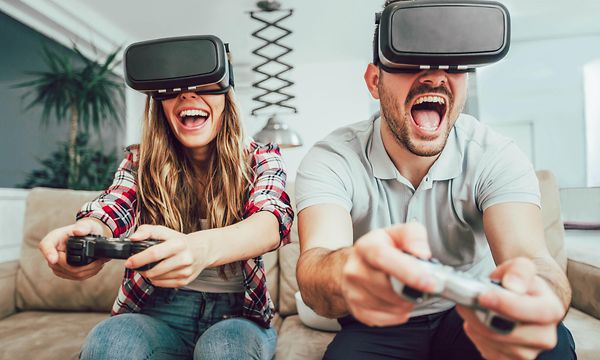 Pariskunta pelaa yhdessä videopeliä VR-lasit päässään