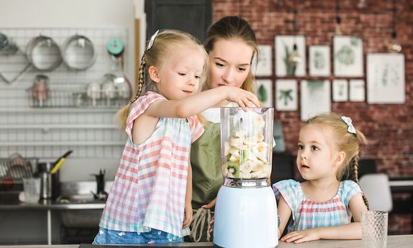 Kaksi lasta tekee smoothieita äitinsä kanssa