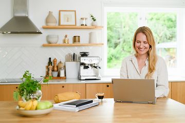 Keittiössä oleva nainen työskentelee kannettavalla tietokoneella