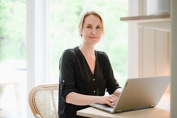 Nainen työskentelee kannettavalla tietokoneella pöydän ääressä