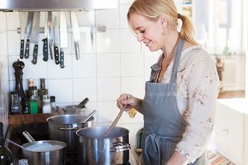 SDA - Ruoanlaitto - Nainen valmistaa päivällistä keittiössä