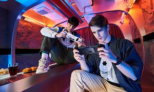 Kaksi kaverusta pelaa omilla ROG phone 6 -puhelimillaan värikkäässä huoneessa