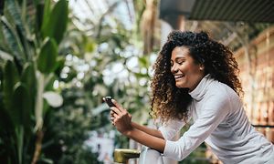 Smiling woman on balcony looking at smartphone