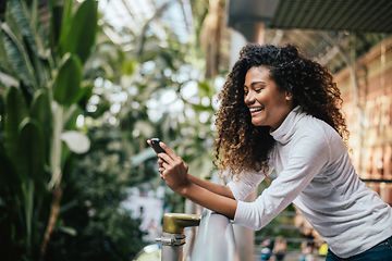 Smiling woman on balcony looking at smartphone