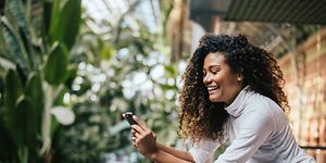 Smiling woman on balcony looking at smartphone