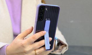Henkilö pitelee Samsung Galaxy S22 -puhelinta kädessään, jossa on laventelin väriset kuoret