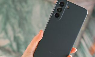 Henkilö pitelee Samsung Galaxy S22 -puhelinta kädessään, jossa on vihreät nahasta valmistetut kuoret