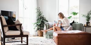 Nainen vauva sylissään istuu valoisassa olohuoneessa