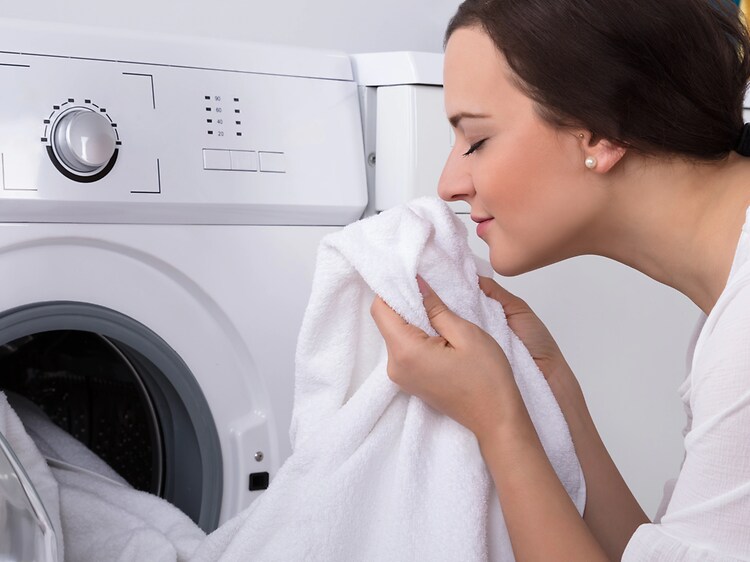 Nainen nuuhkii vastapestyn puhtaan pyykin raikasta tuoksua