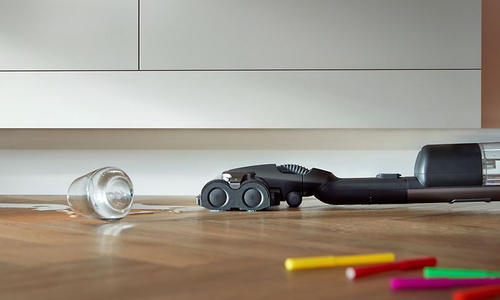 Philips AquaTrio -varsi-imuri imuroimassa kaapin alta