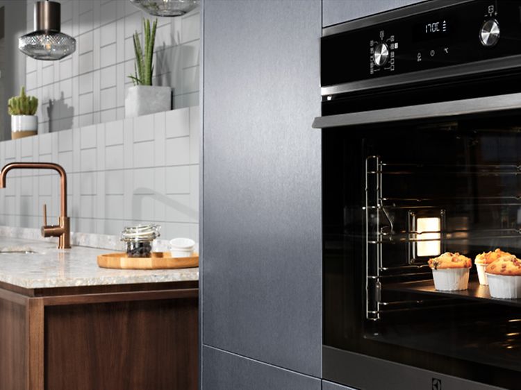 Electroluxin tuplauuni, jonka sisällä muffinsseja paistumassa ja taustalla tiskiallas