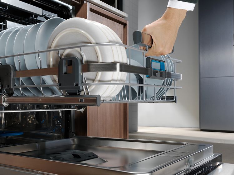 Mies tyhjentää astioita Electroluxin integroitavasta astianpesukoneesta
