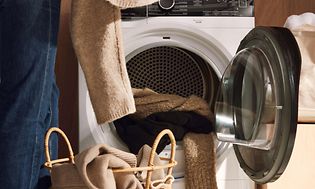 Electrolux - Kuivausrummut - Pyykinhuolto - Henkilö laittaa pyykkiä kuivausrumpuun