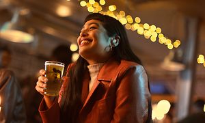 Jabra Elite 5 -kuulokkeet korvissaan oleva tyttö lasillinen olutta kädessään