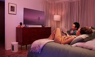 Sängyssä makoileva pariskunta katsoo yhdessä televisiota