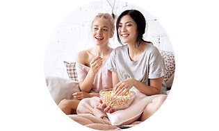 Äiti ja tytär syövät popkornia sohvalla