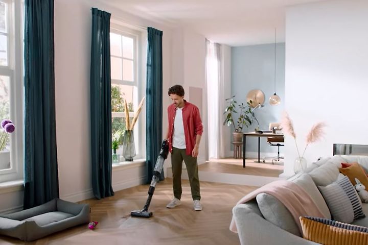 Mies siivoaa Philips AquaTrio -imurilla.